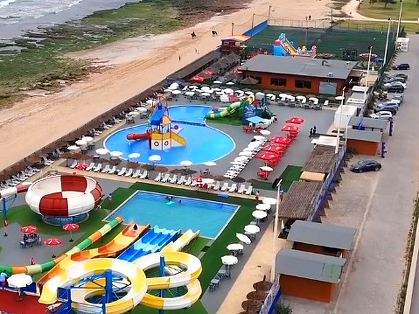 Le parc aquatique Aquamazagan vu du ciel : toboggans et bassins face à la plage