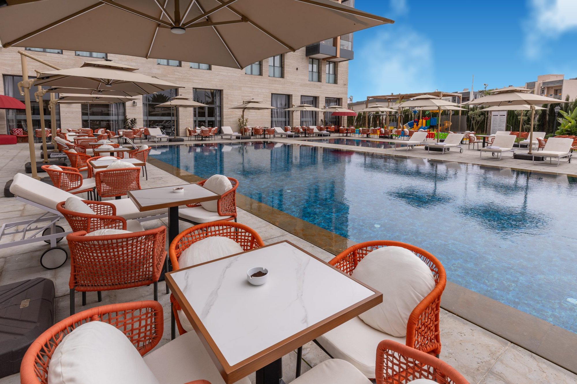 La piscine et ses tables, face aux jardins