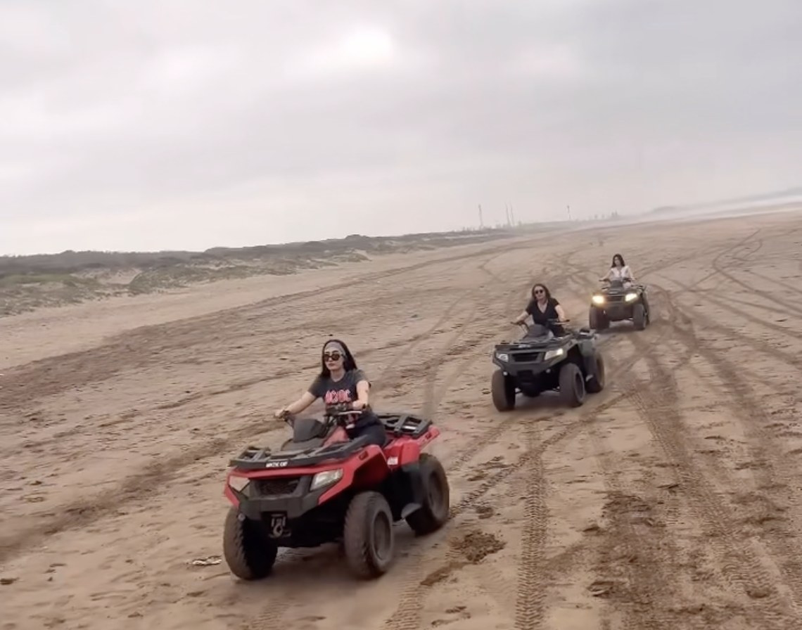 Trois quads sur une longue plage de sable, au bord de l'océan