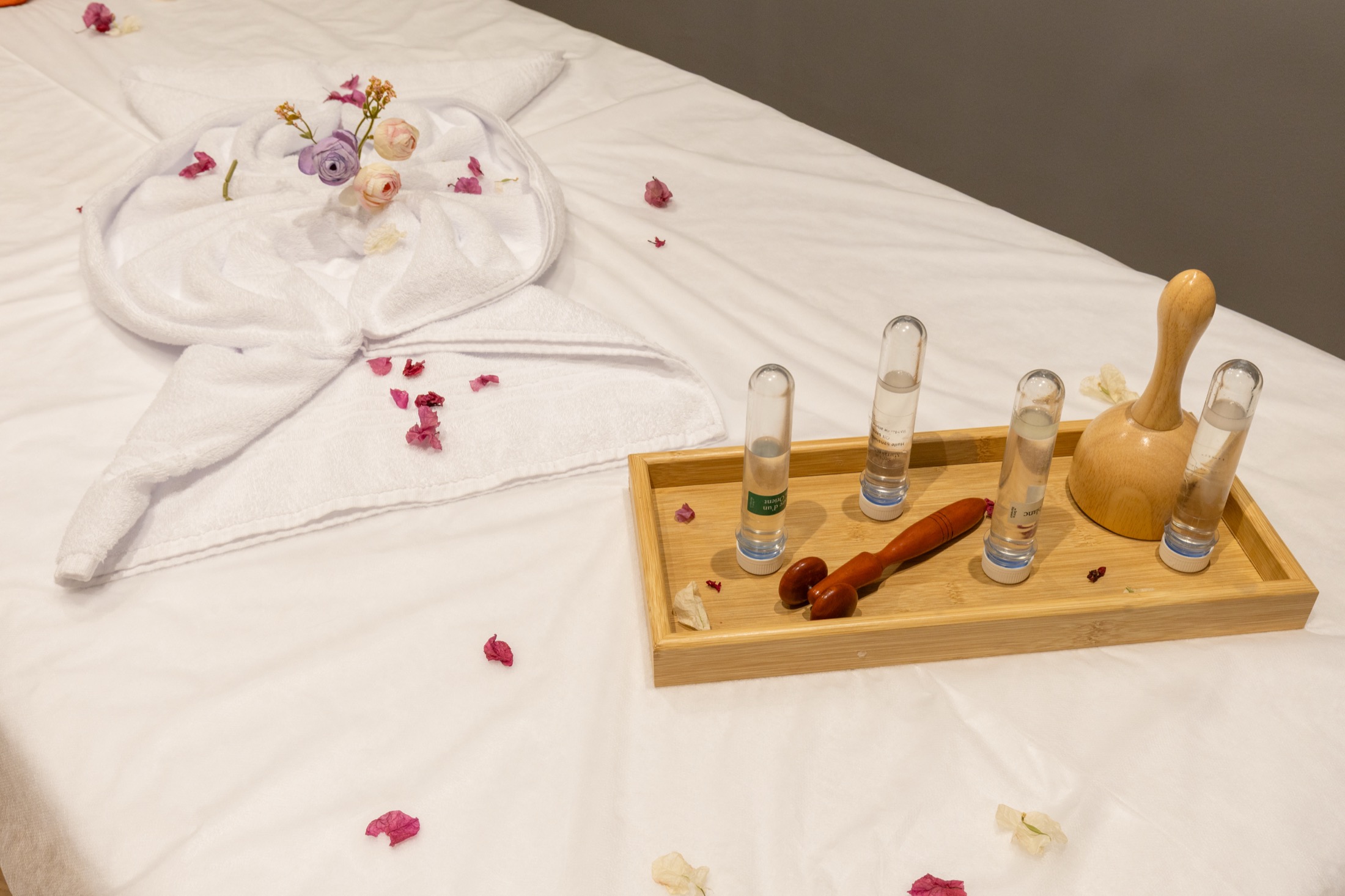 Plateau de soins avec huiles de massage et pétales de fleurs, sur la table de massage